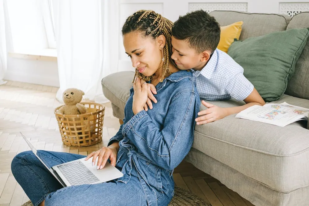 mom sitting on floor with laptop with son